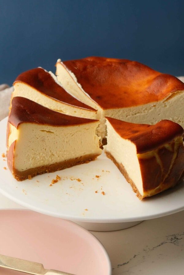 whole san sebastian cheesecake on a white cake stand.
