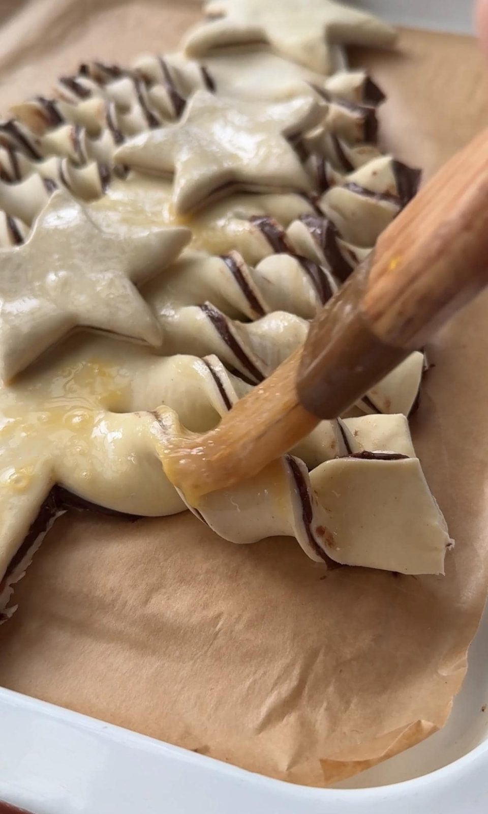 brushing the puff pastry christmas tree with egg wash.