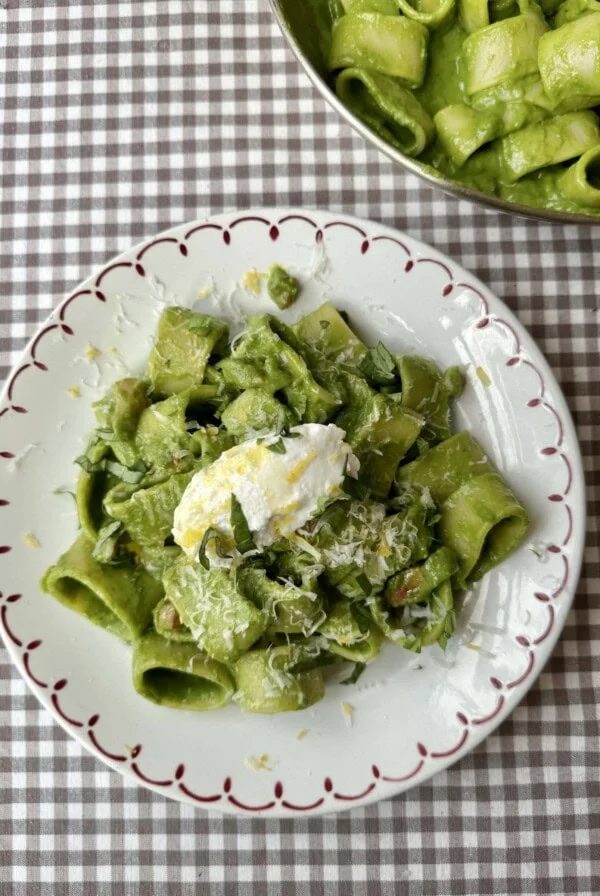 pasta in green sauce on a plate topped with cheese