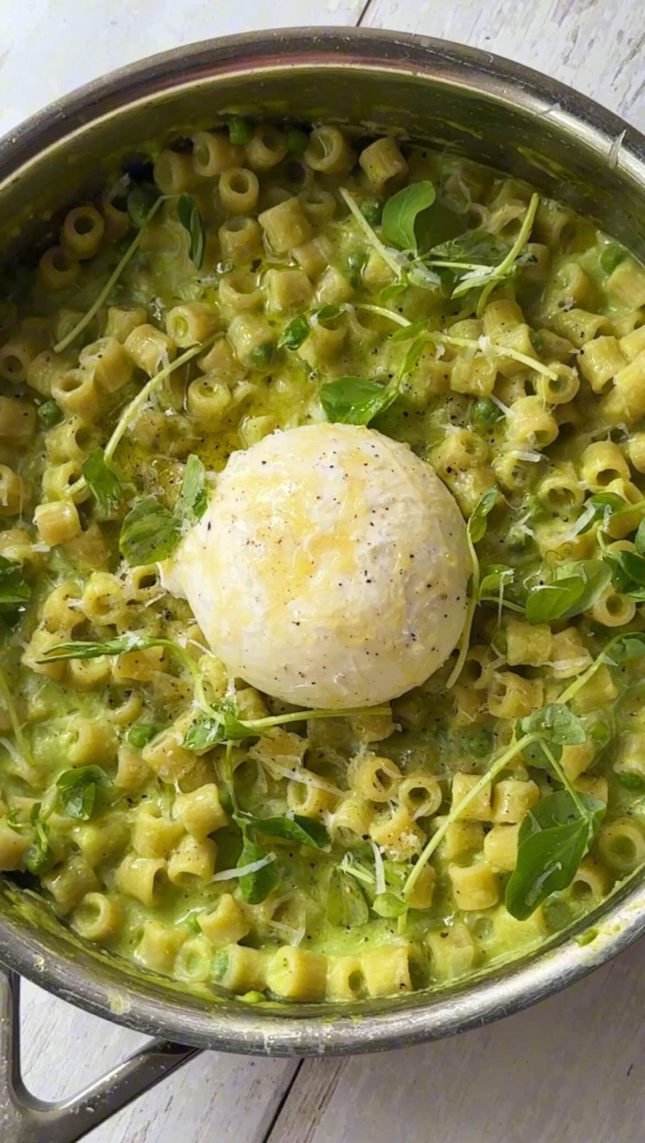 adding burrata on top of pasta and peas.