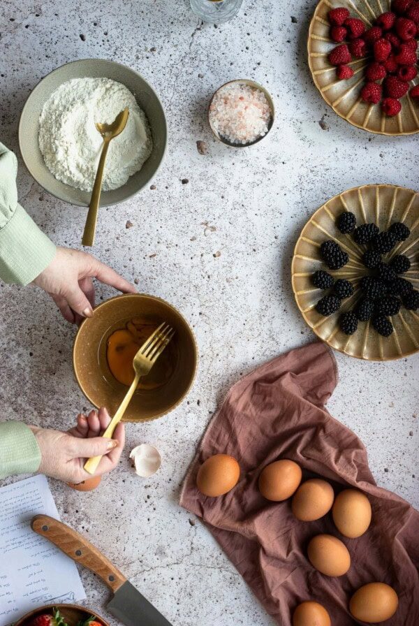 woman whisking eggs with flour and chocolate around.