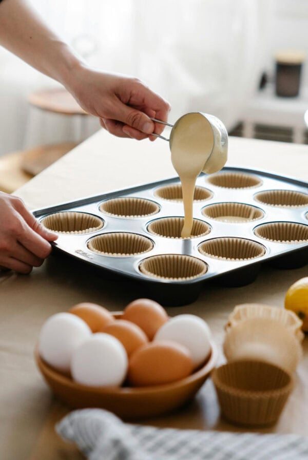 woman filling muffin cases up with batter.