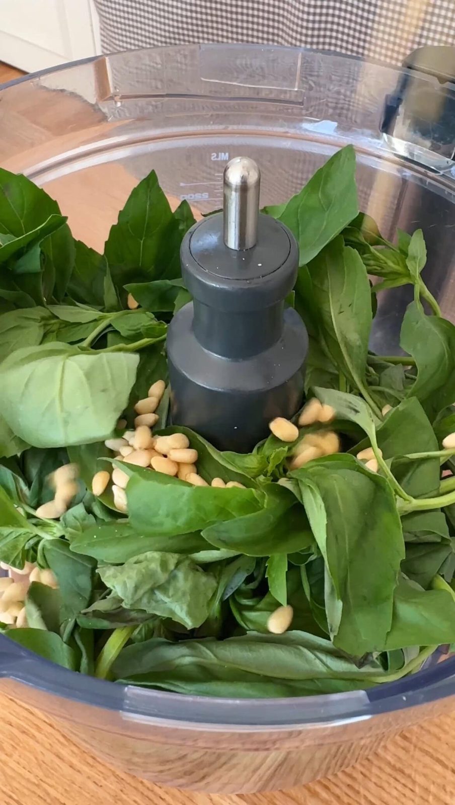 Fresh basil in food processor with pine nuts.