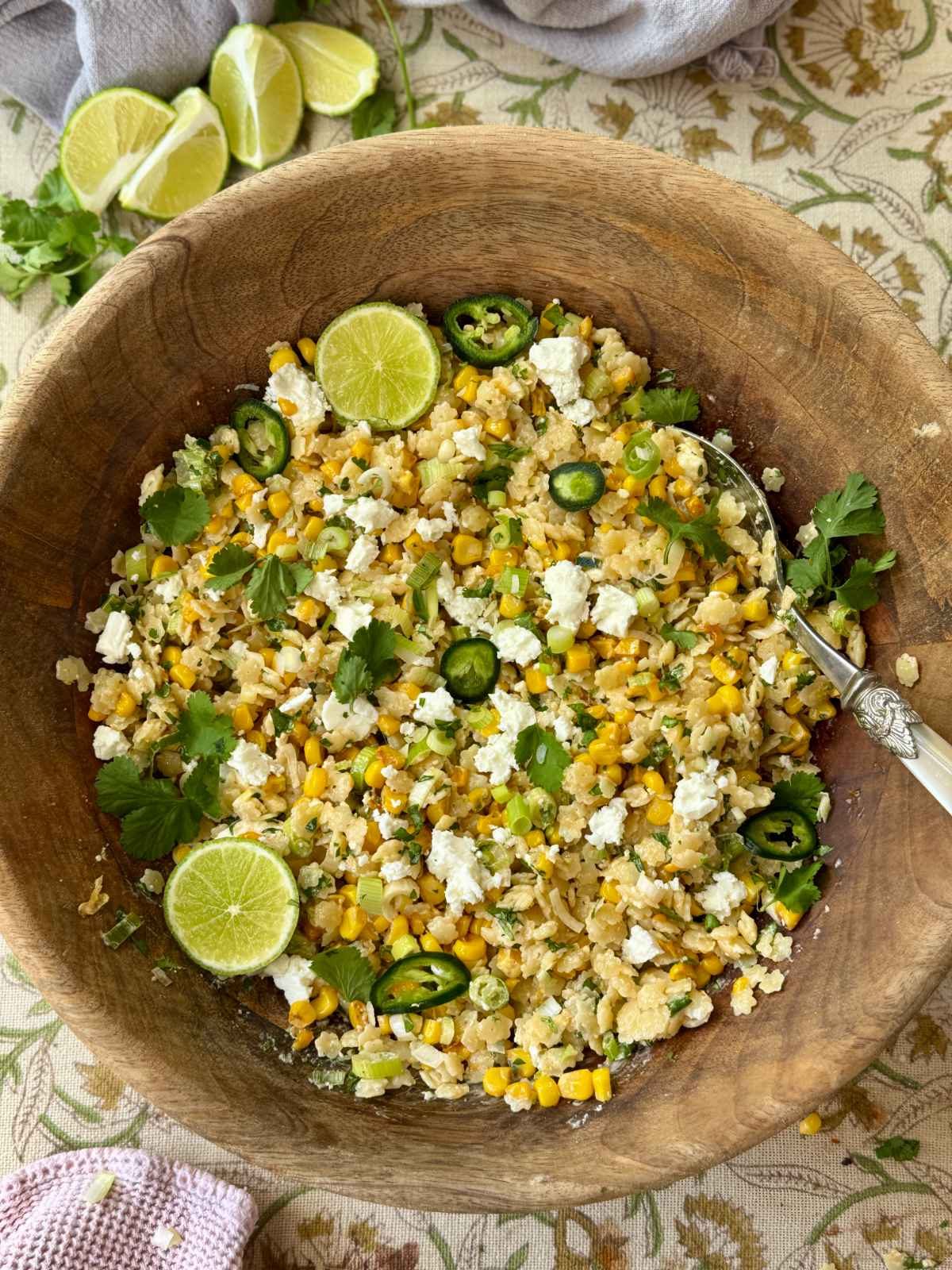 pastina salad in a wooden bowl with lime slices and feta.