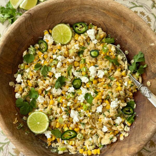 pastina salad in a wooden bowl with lime slices and feta.