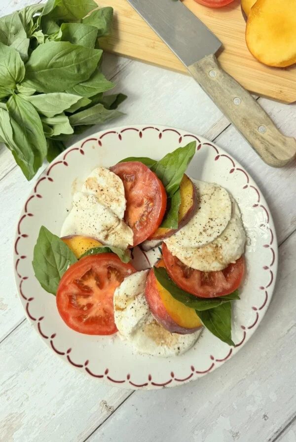 peach caprese on a white plate with red rim