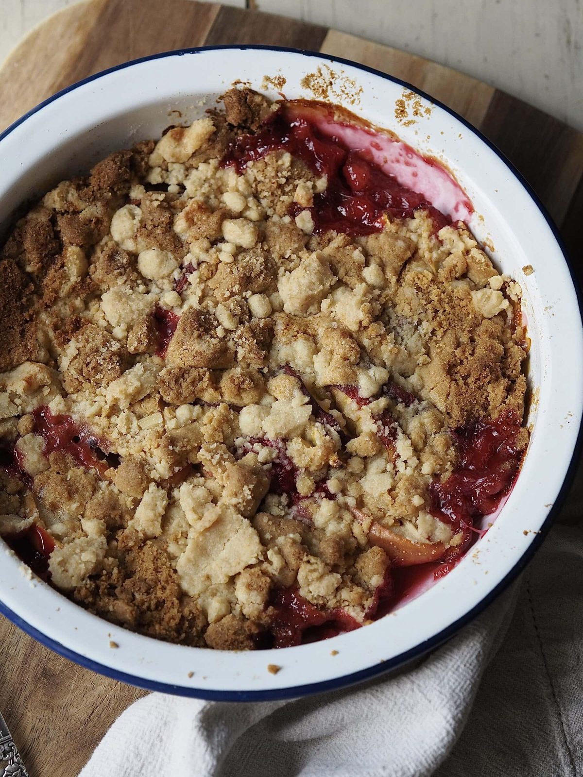 Baked peach cobbler with apples and raspberries in baking dish.
