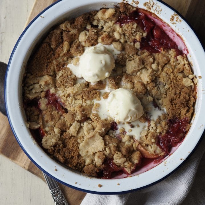 Peach cobbler in bowl with ice cream.