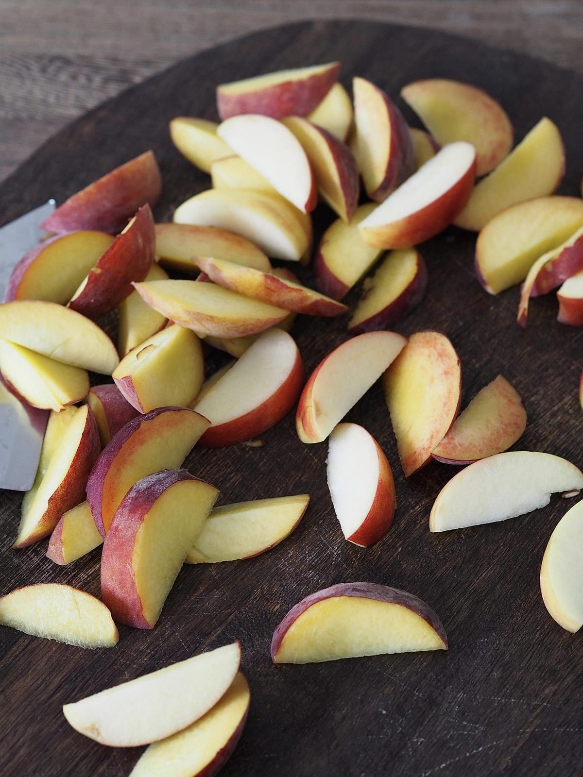 Freshly sliced apples and peaches on cutting board.