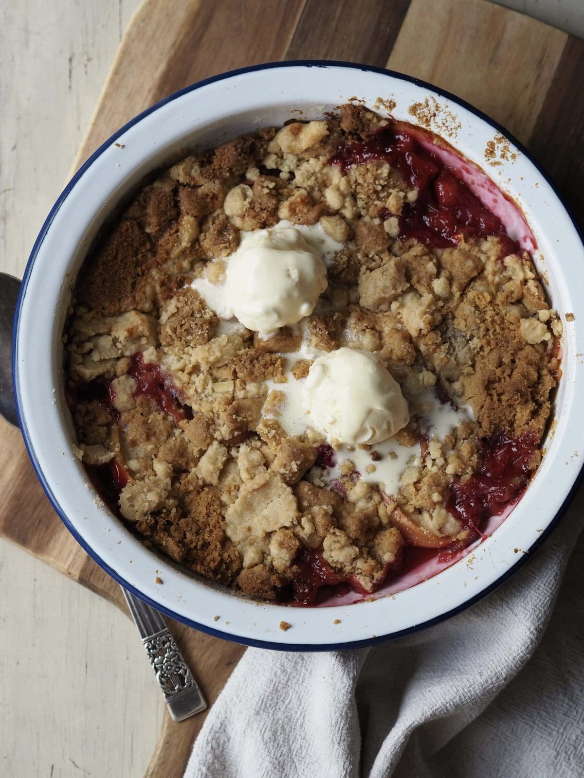 Peach cobbler in bowl with ice cream.