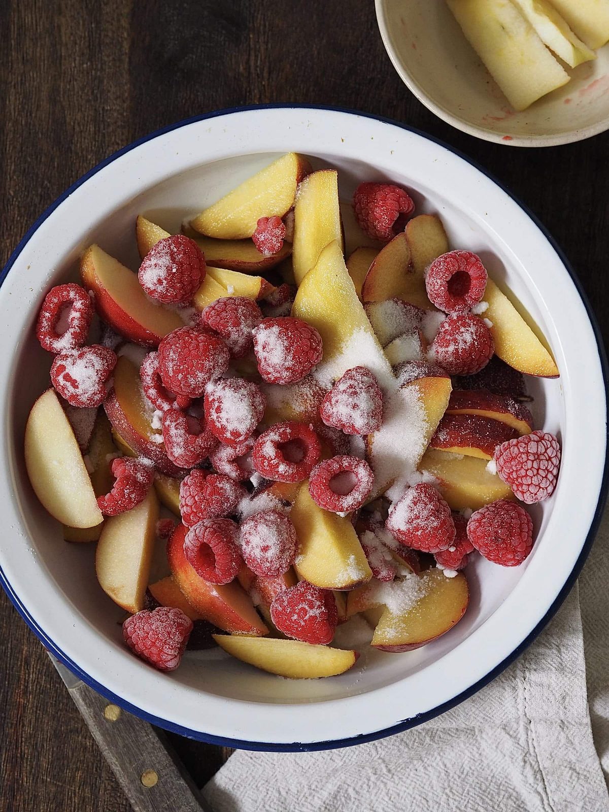 Raspberries and sugar on top of sliced peaches and apples.