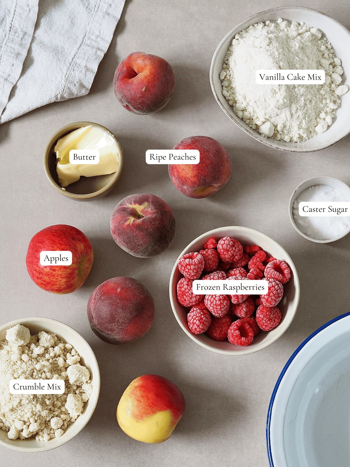 Peaches, apples, raspberries, cake mix, and other ingredients on table.