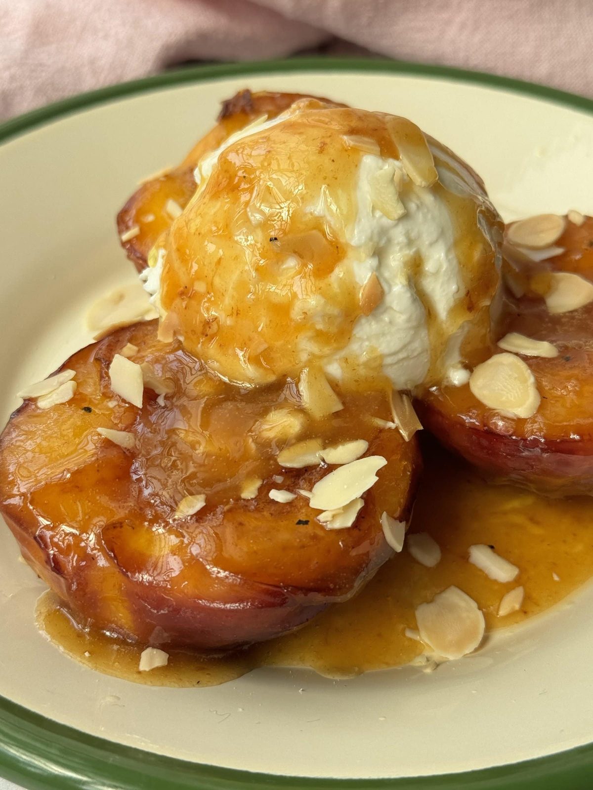 peaches and cream on a white plate with green trim.