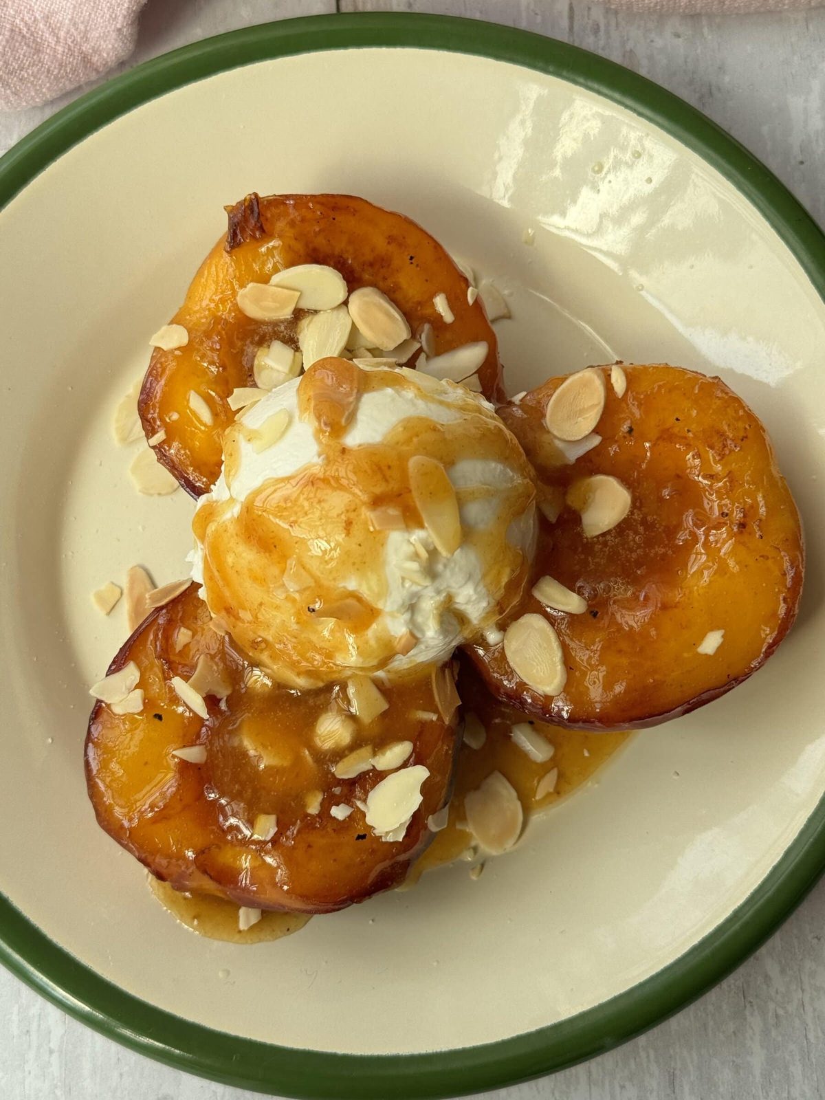 peaches and cream on a white plate with green trim.