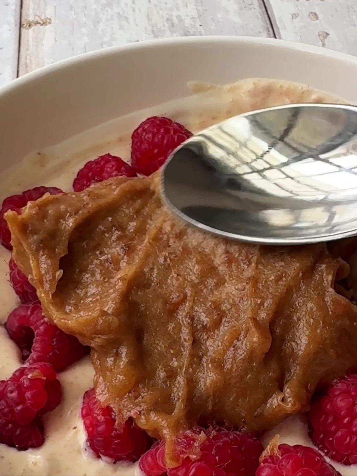 Spooning date caramel over raspberries.
