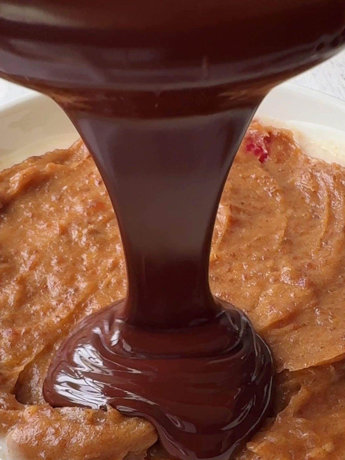 Pouring melted chocolate over date caramel.