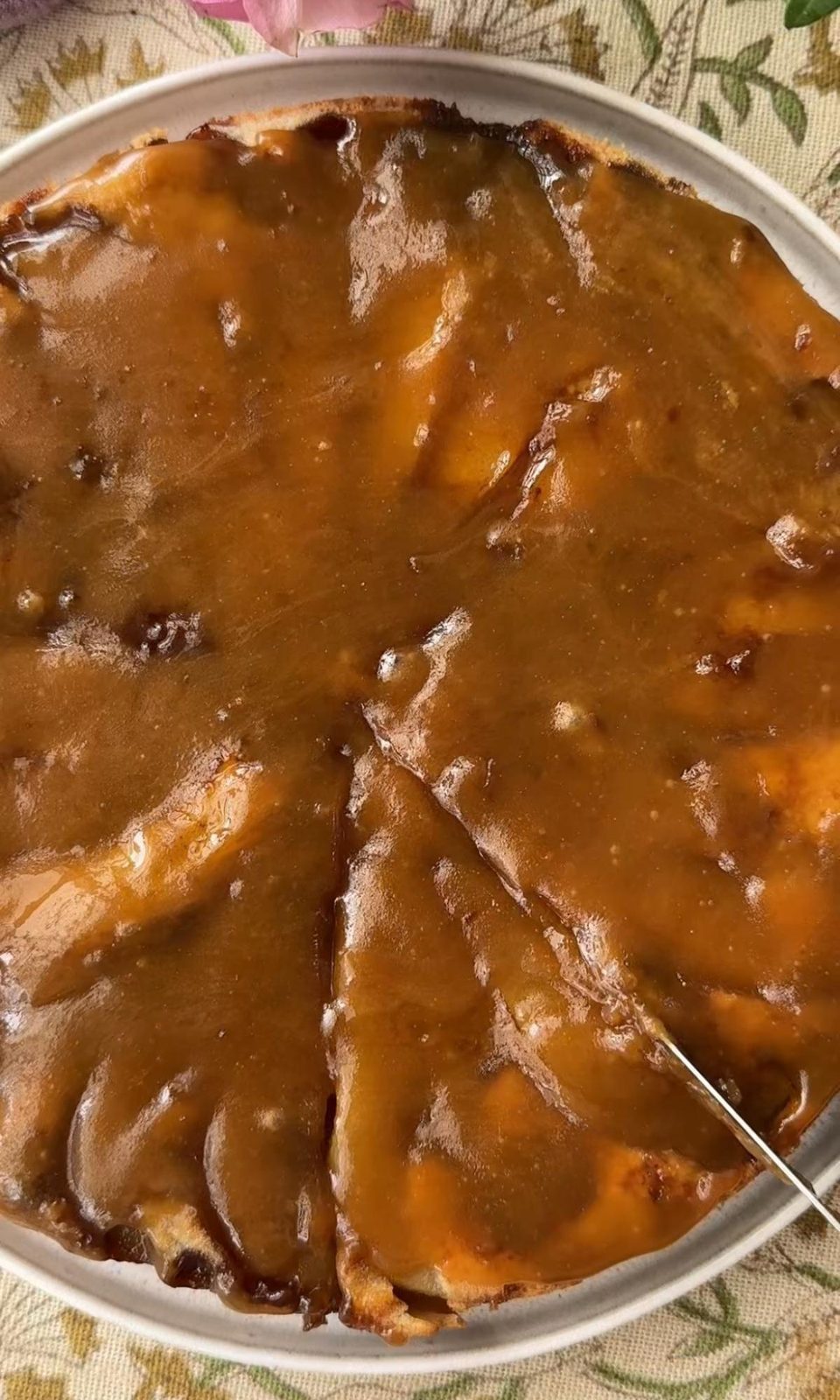 pouring fudge sauce on pear cake.