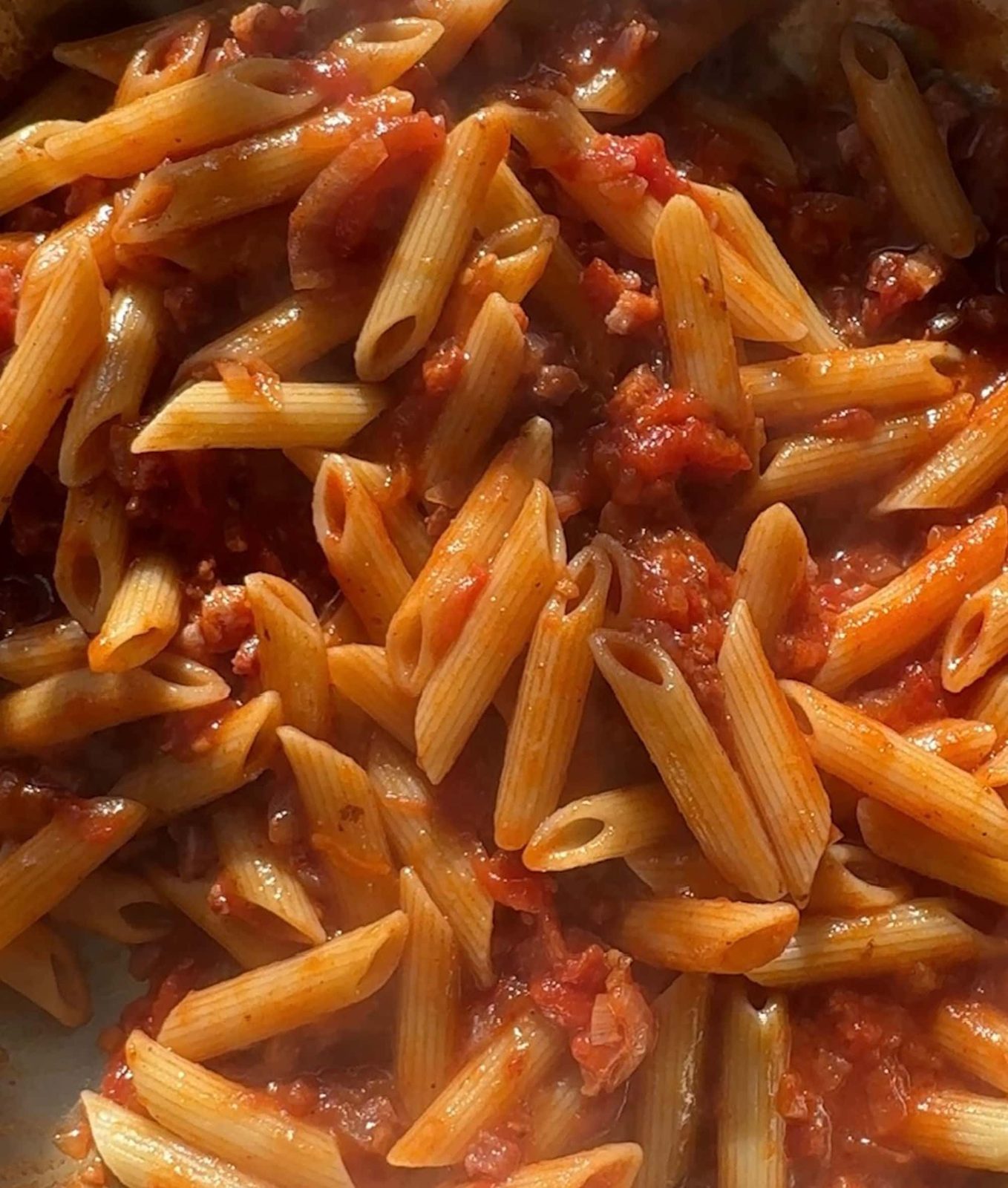 Tossing amatriciana sauce with penne.