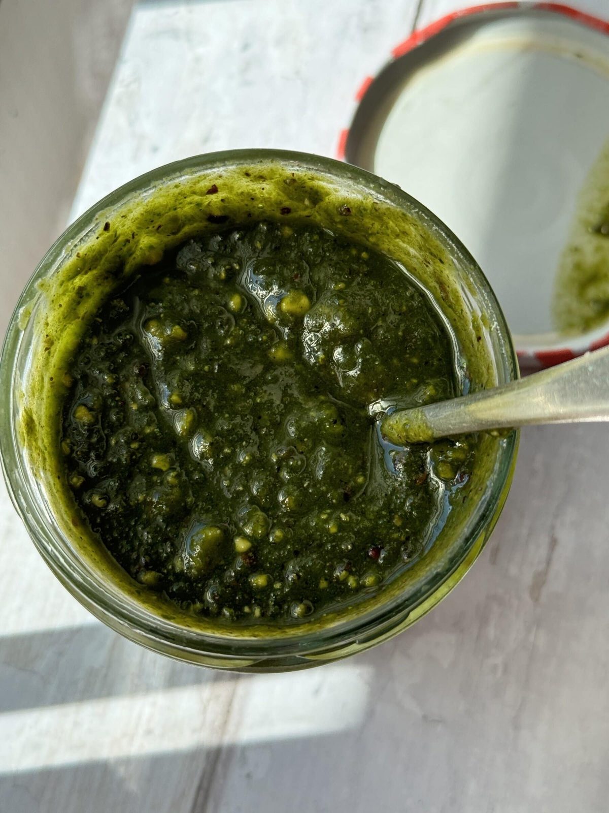 Pistachio pesto in small jar with spoon.