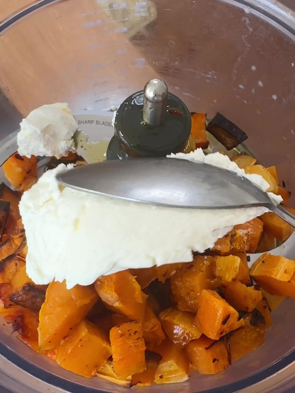 Adding ricotta to roasted butternut squash in food processor.