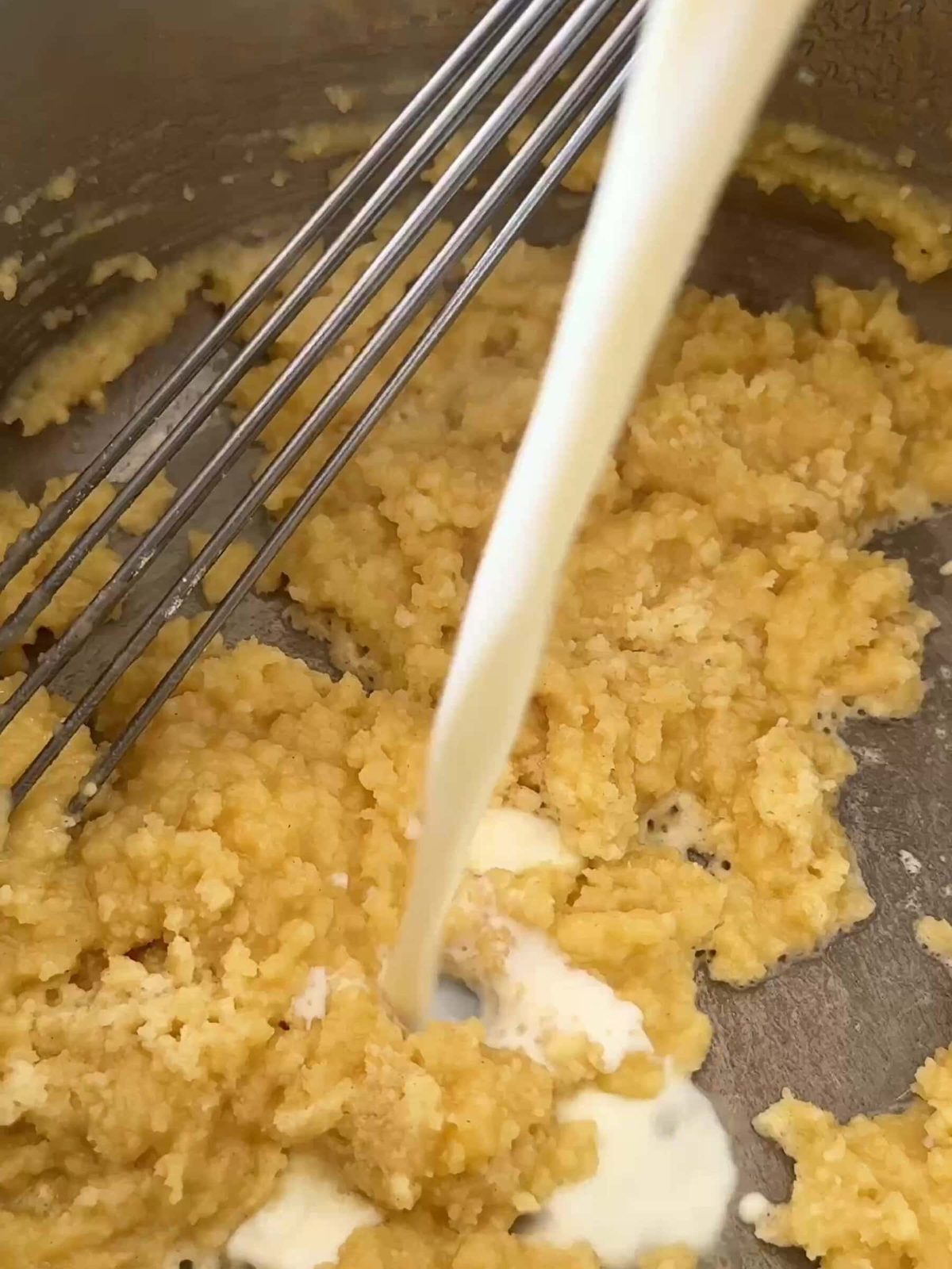 Pouring milk into bechamel sauce in pan.