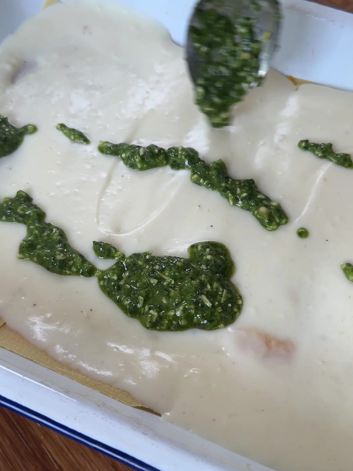 Adding pesto to the lasagne.