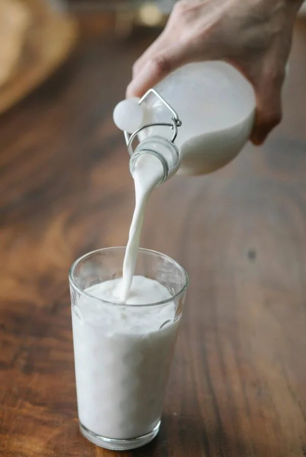 Woman pouring milk into a pint glass.