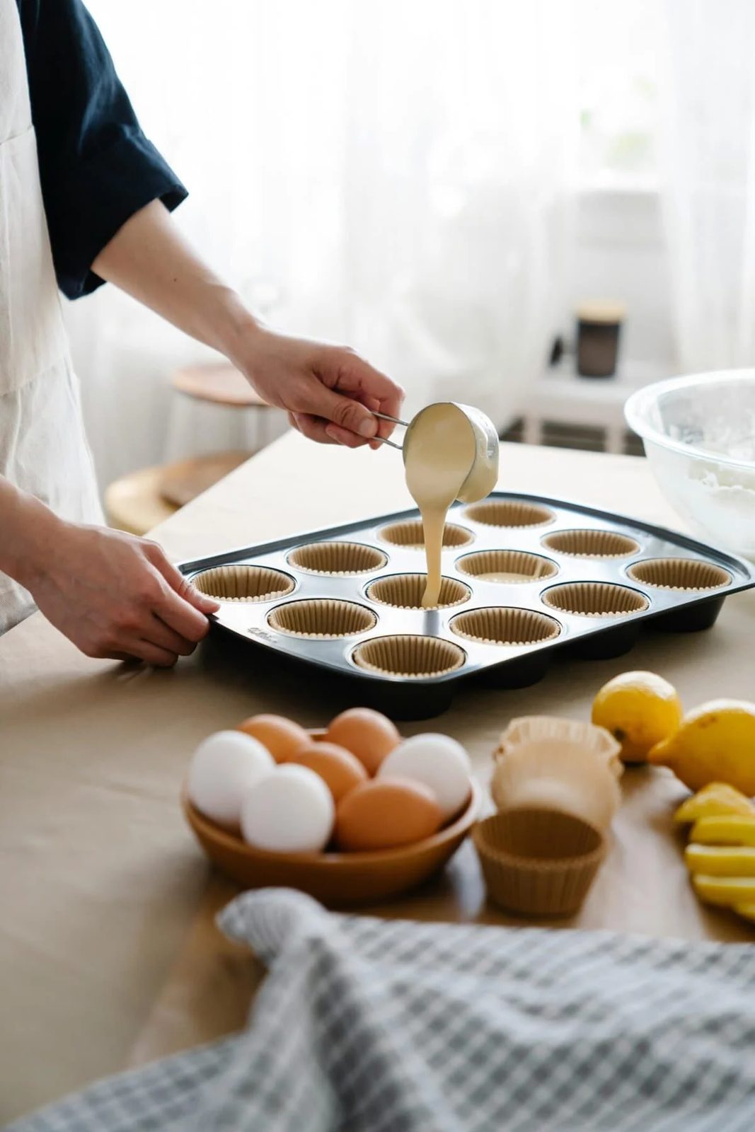 woman filling muffin cases up with batter.