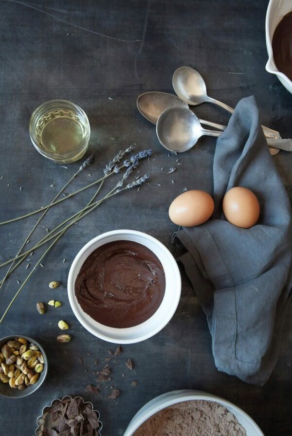 Baking ingredients laid out on a dark background with eggs and a bowl of melted chocolate.
