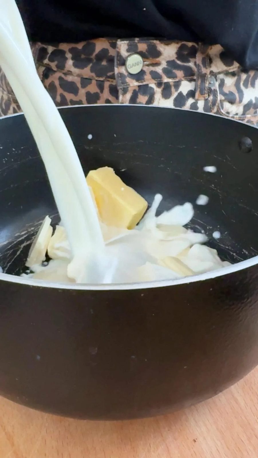 adding milk to butter and white chocolate in a pan.