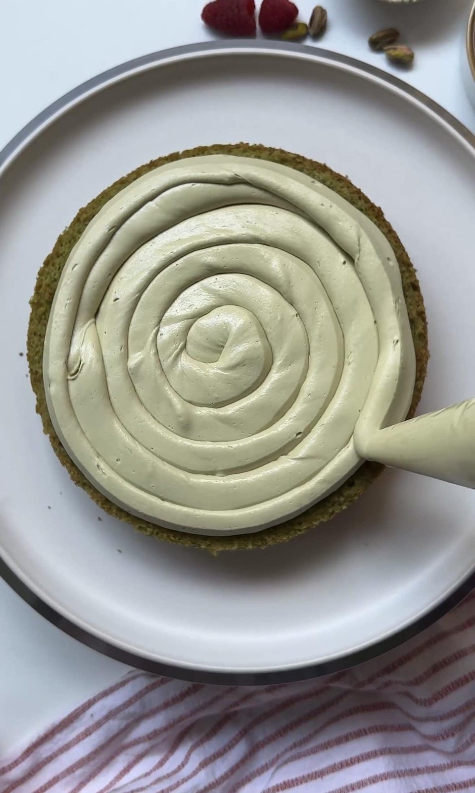 Piping pistachio icing onto the pistachio sponge.