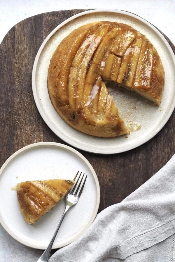upside down banana cake on a white plate with a slice out