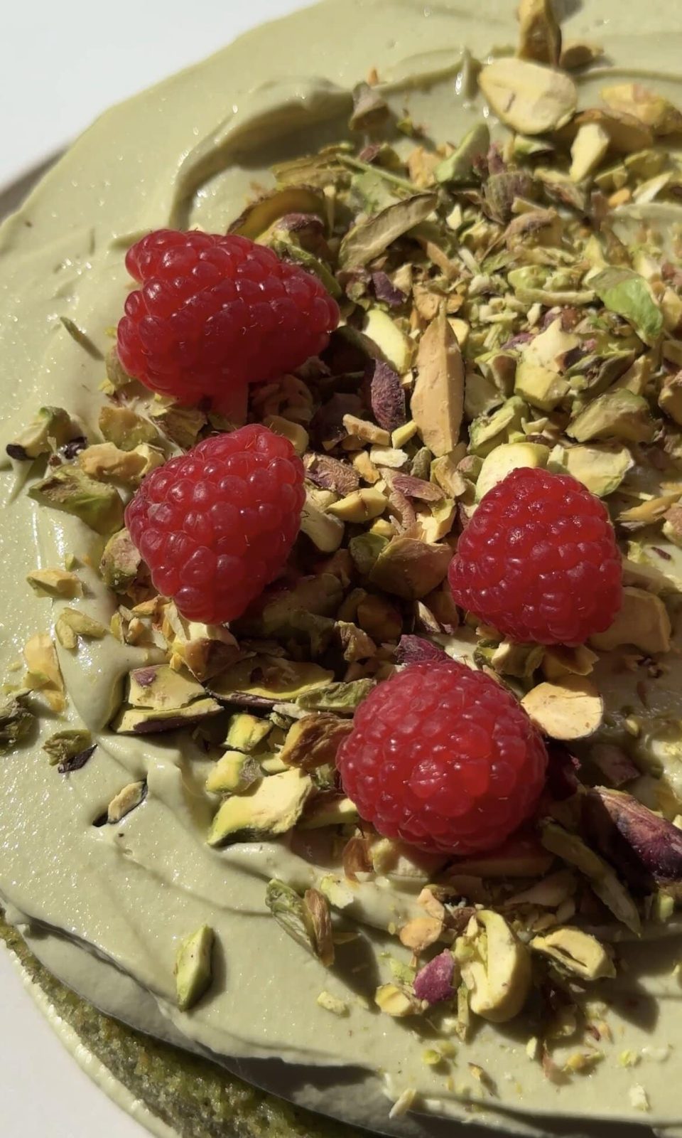 Adding raspberries and pistachios on top of the cake.