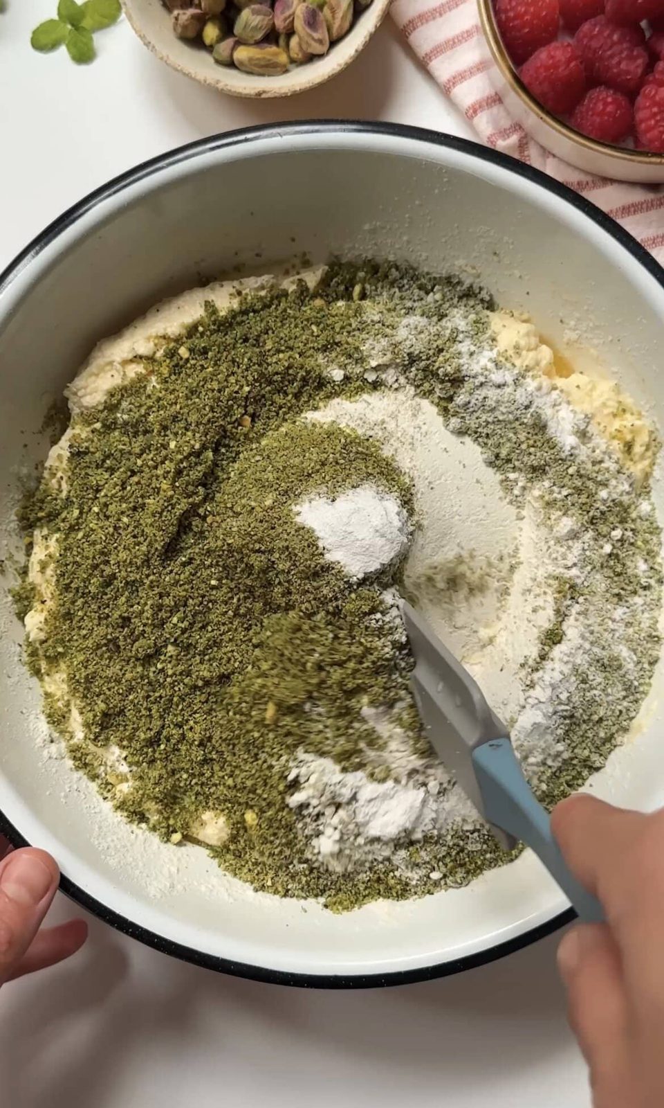 Folding pistachios into the sponge batter.