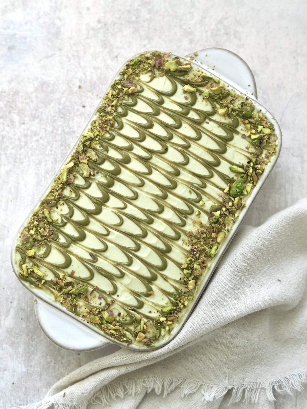 Finished pistachio tiramisu with pistachio cream decoration in pan.