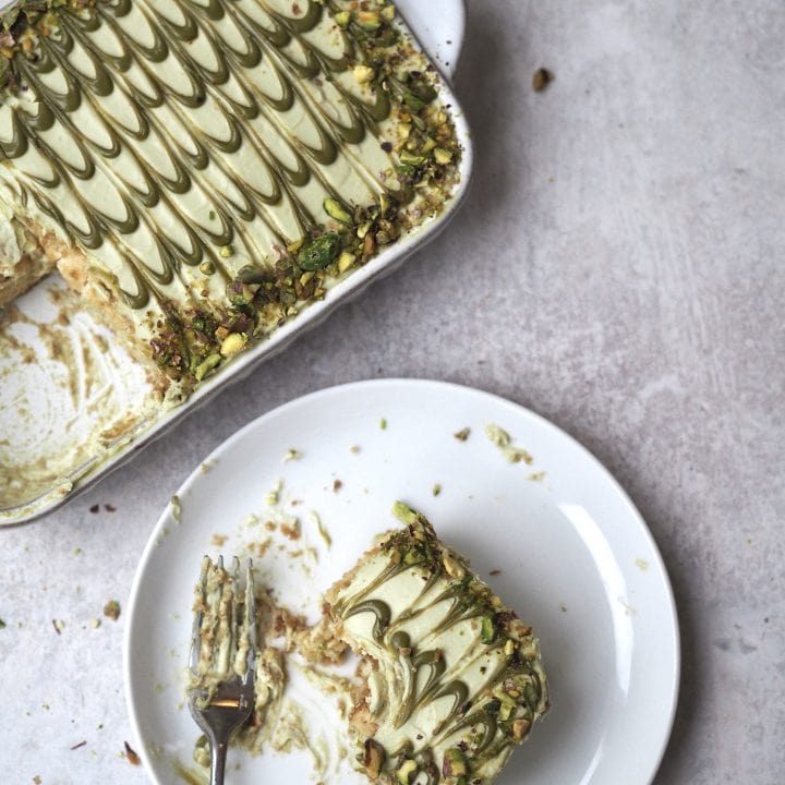 pistachio tiramisu in white dish with slice on a plate.