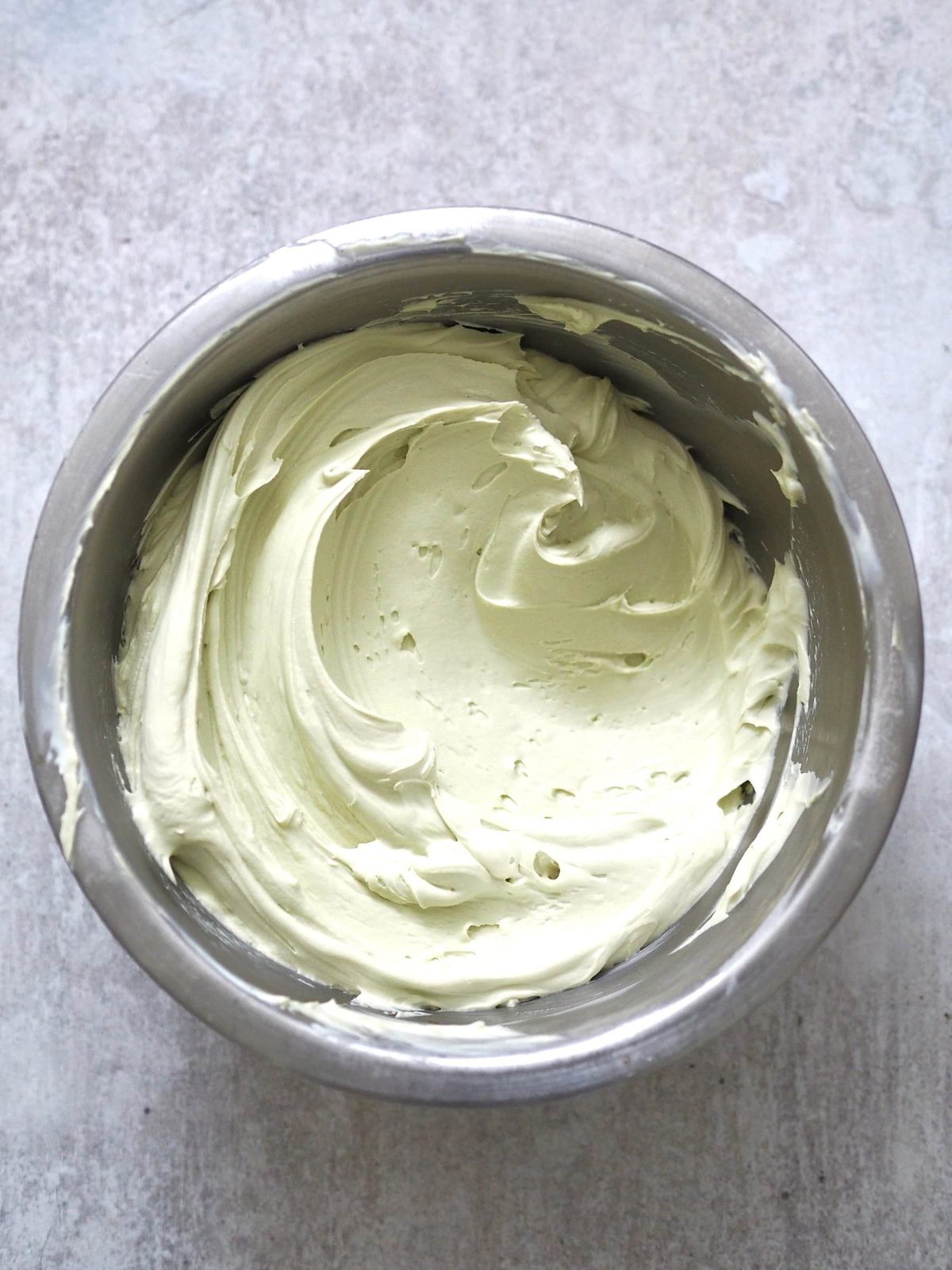 Pistachio whipped cream in metal bowl.