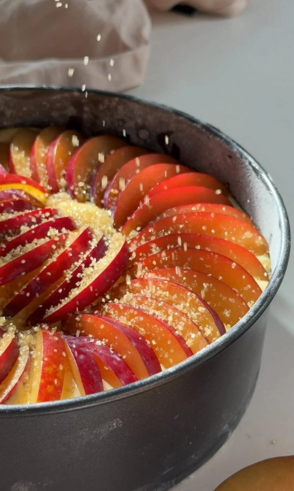 Sprinkling demerara sugar on the plum yogurt cake.