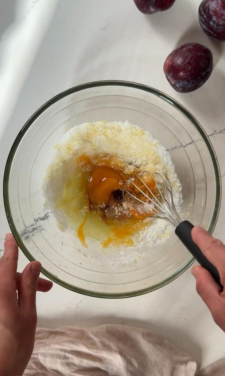 Whisking eggs and lemon sugar in glass bowl.