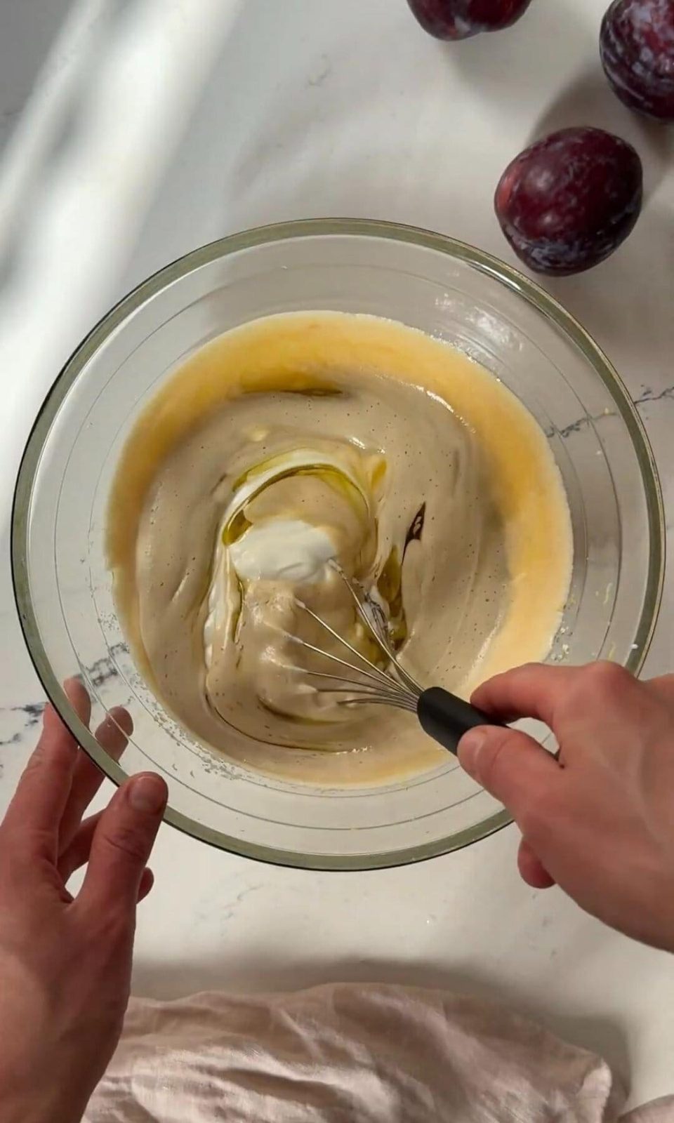 Mixing yogurt and oil into cake batter with whisk.