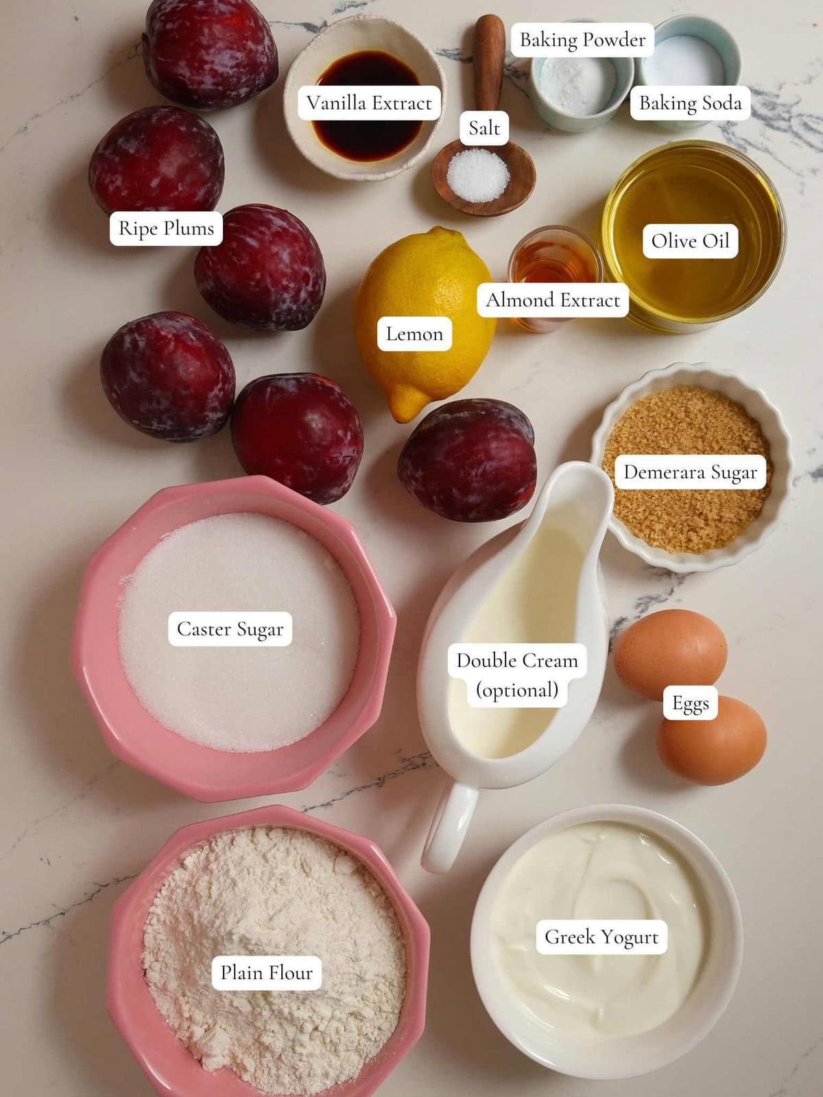 Sugars, flour, yogurt, cream, fresh plums and lemon, and other cake ingredients on table.