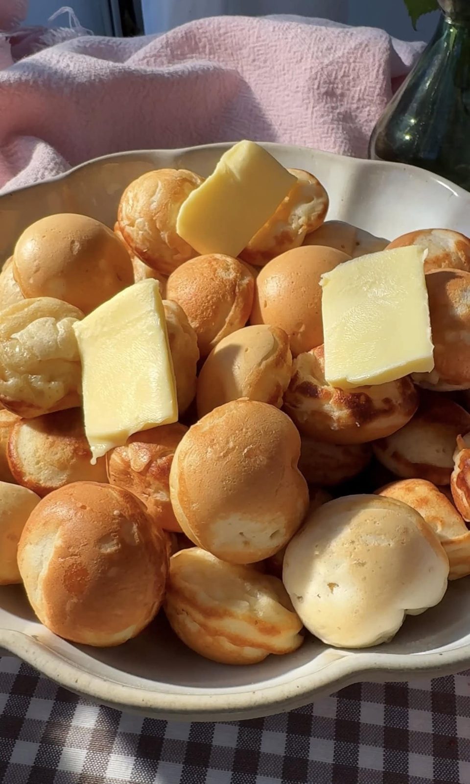 cooked poffertjes in a large bowl with butter on top.