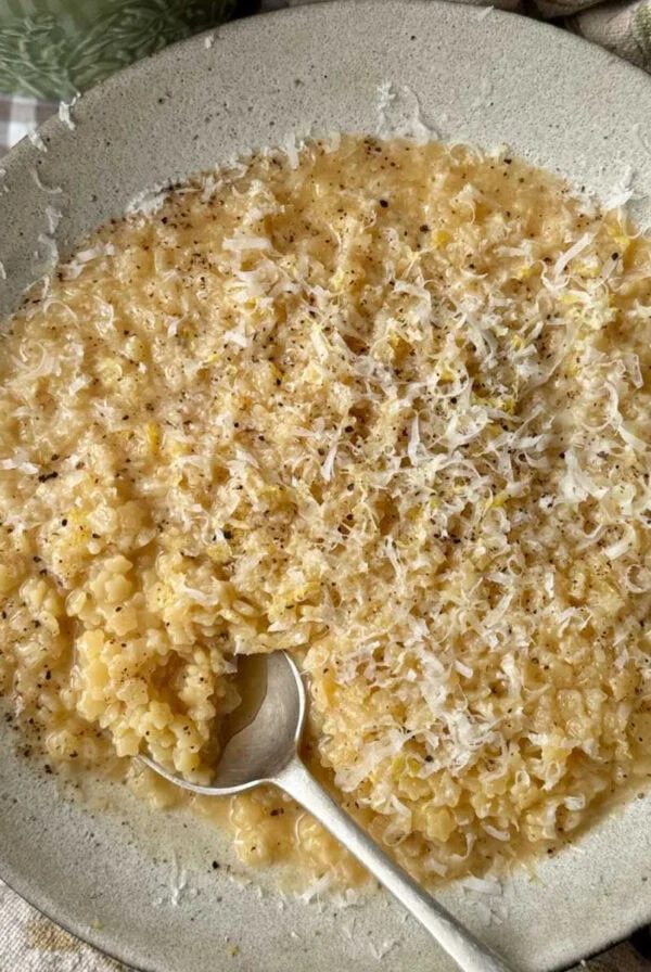 A bowl of creamy pastina with a spoon in the bowl.