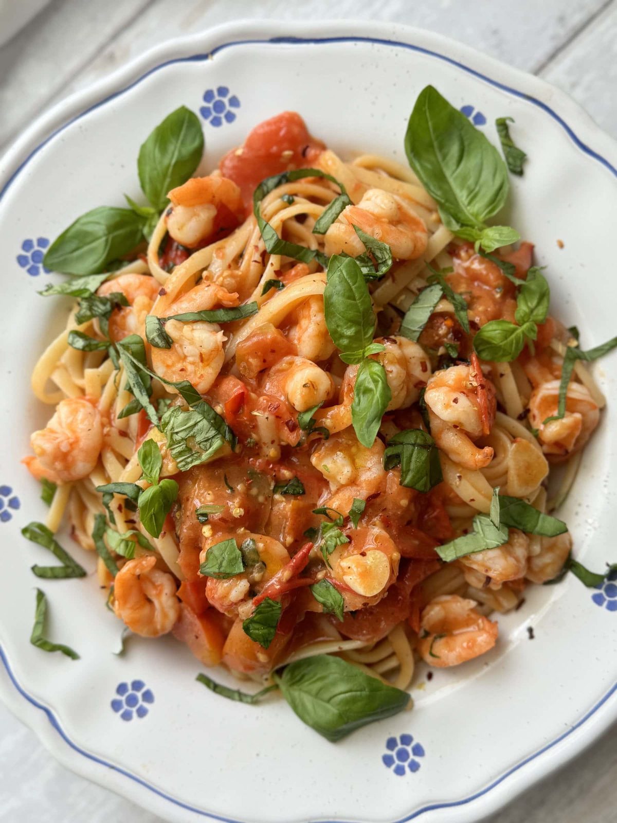 A plate of prawn tomato linguine with fresh basil.