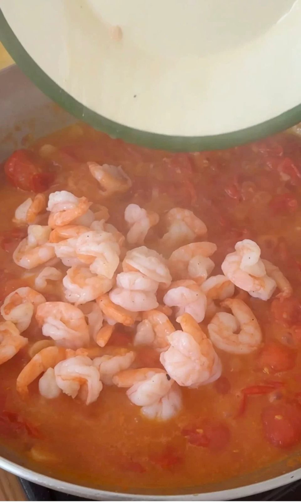 Adding prawns to tomato sauce.