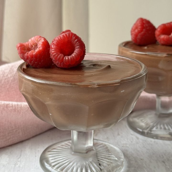 chocolate protein mousse in a glass coupe with raspberries on top