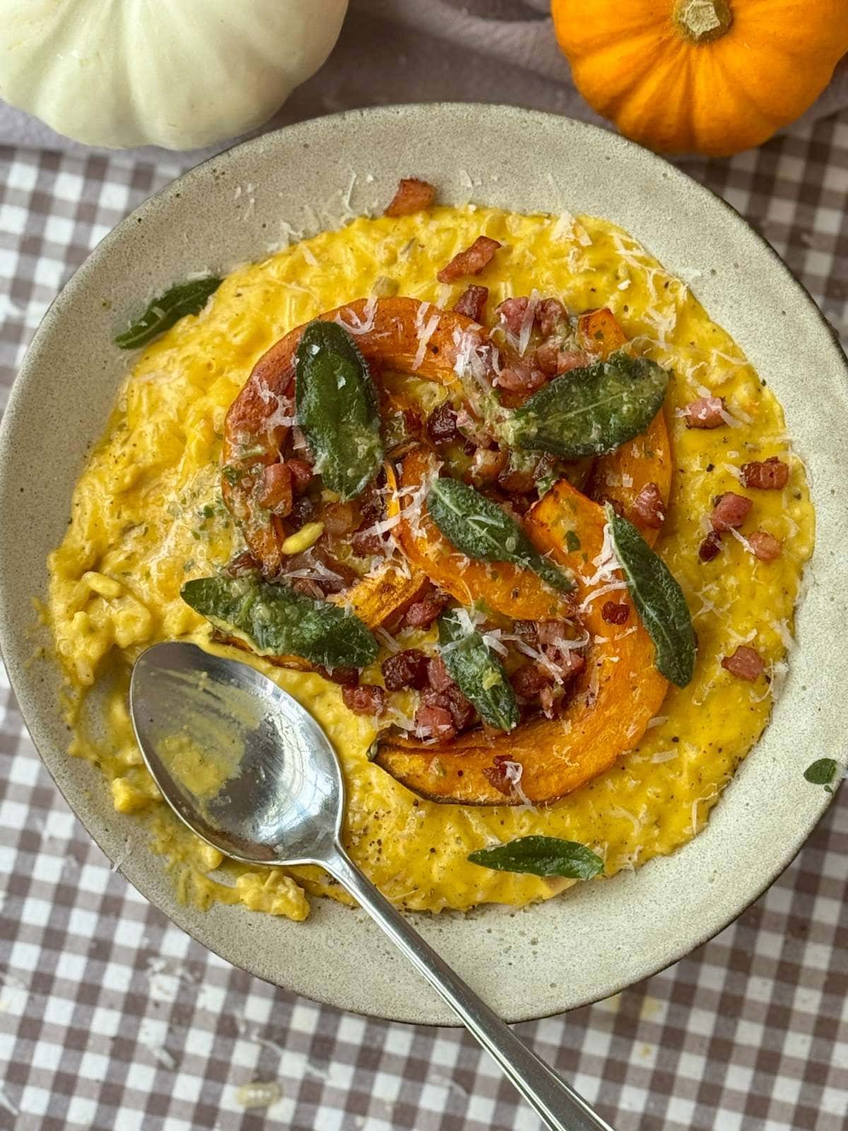 Pumpkin risotto in a grey bowl with a spoon.