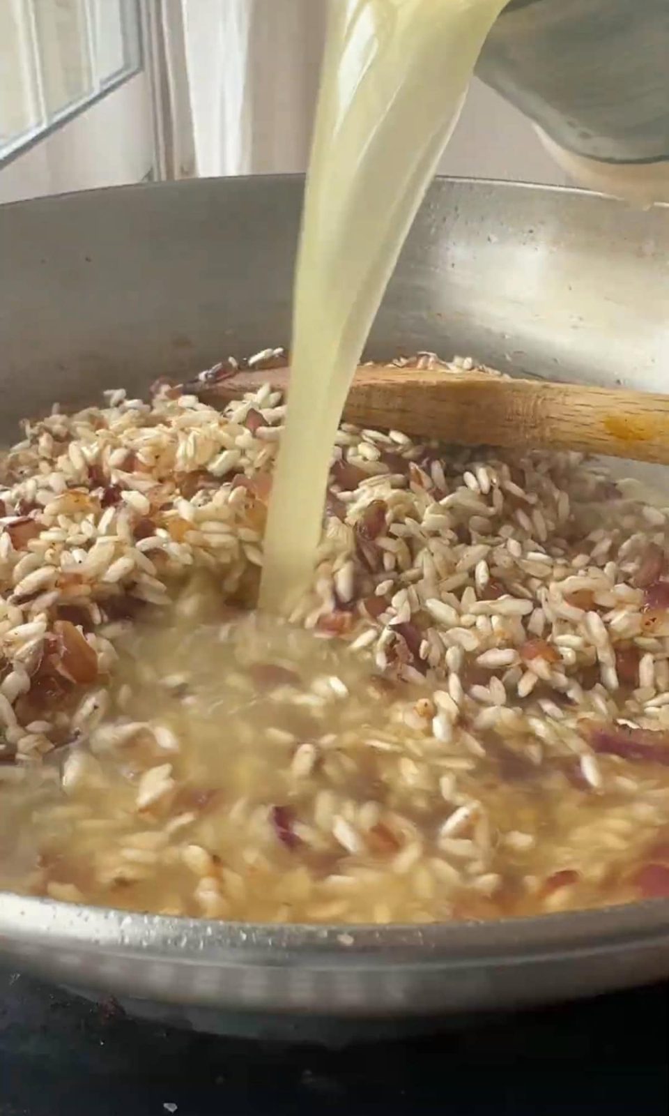 Pouring stock into pan to make risotto.