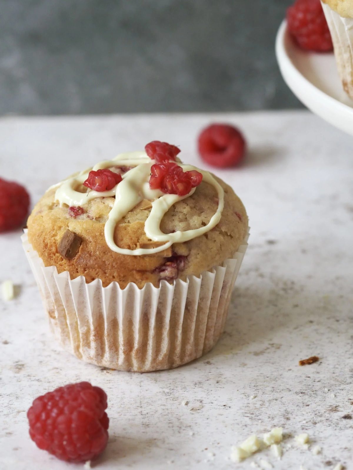 A muffin with fresh raspberries and white melted chocolate