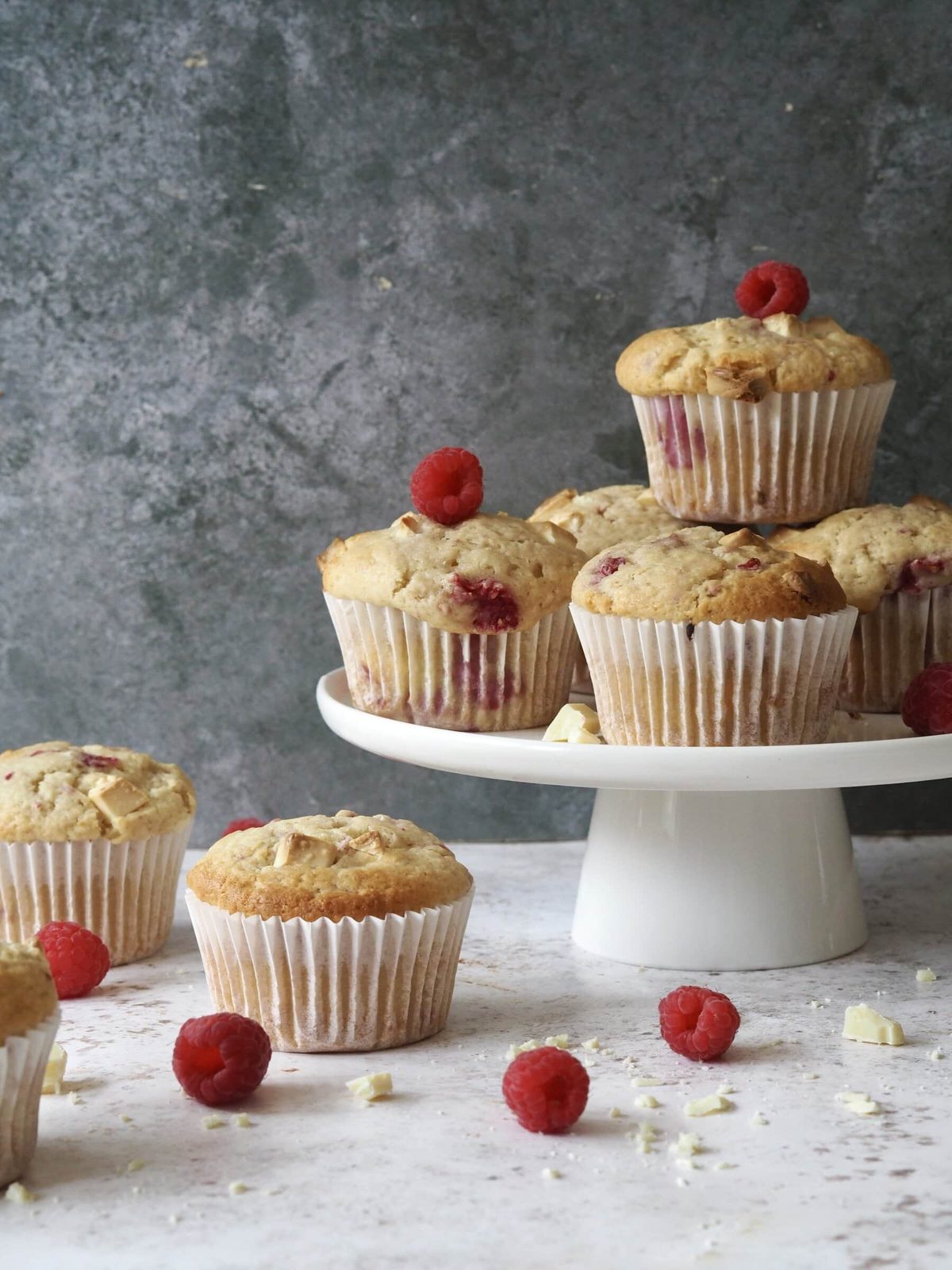 Raspberry White Chocolate Muffins on a white cake stand.